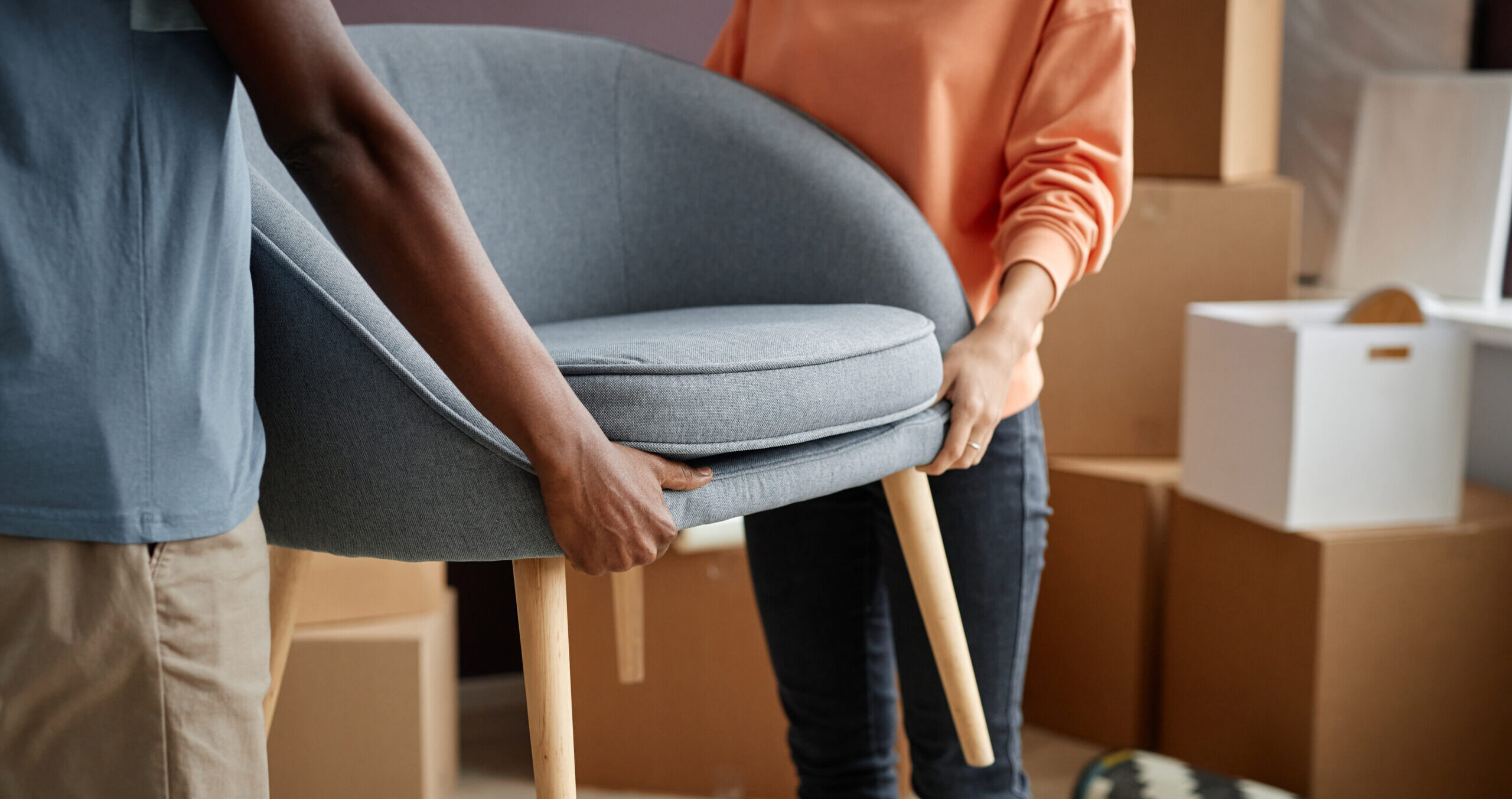 Close-up of young couple carrying furniture in new apartment during relocation